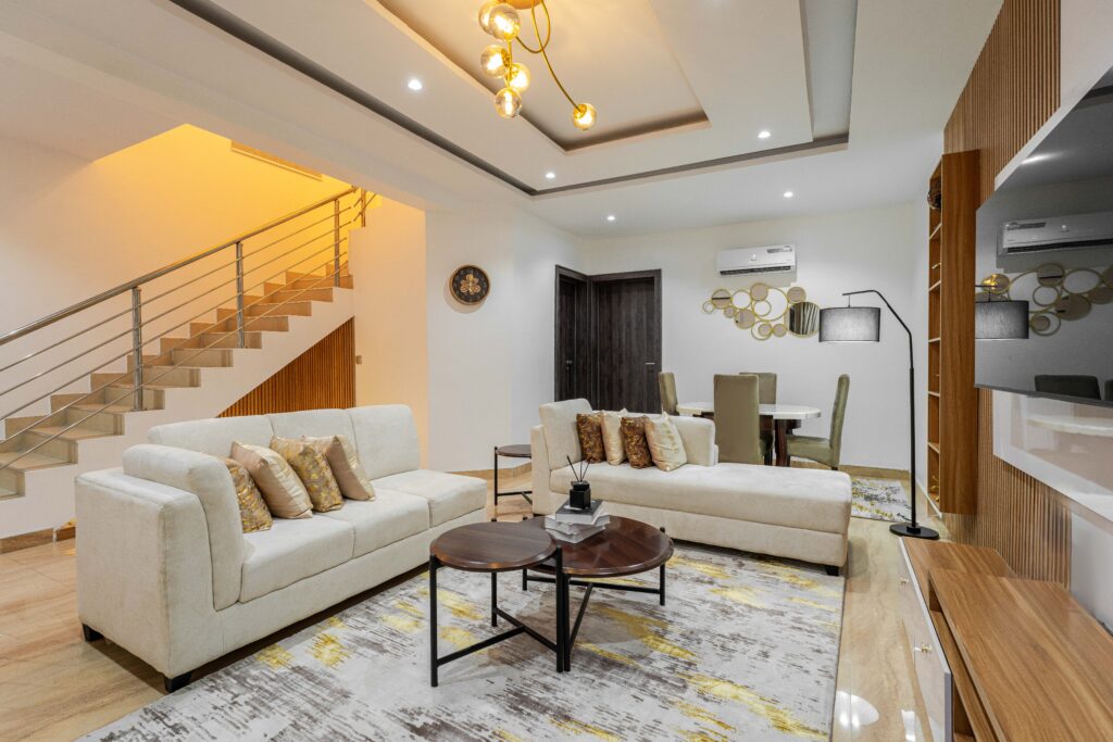 Duplex living room with brass pendant lighting and staircase at George Residence